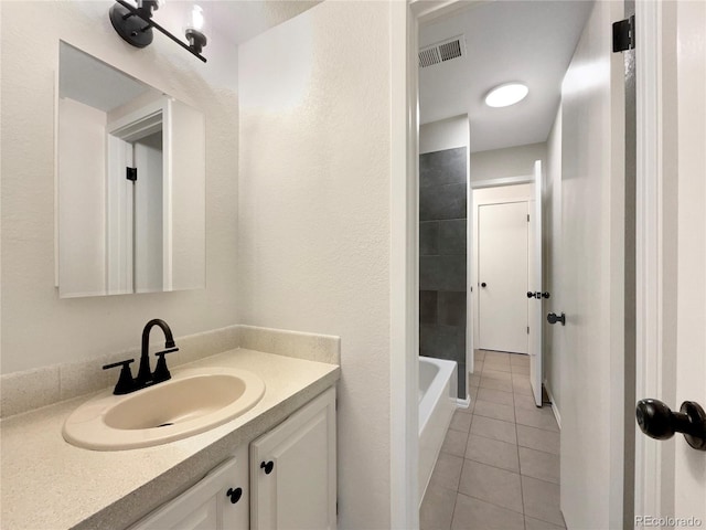 bathroom featuring tile patterned flooring, a bath, and vanity