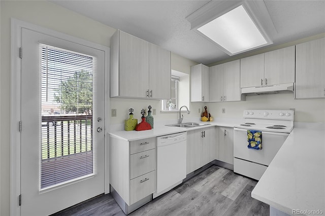 6737 Overland Dr, Colorado Springs, CO 80919 - kitchen featuring light countertops, a sink, light wood finished floors, under cabinet range hood, and white appliances