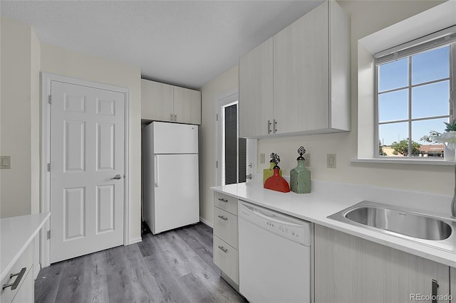 6737 Overland Dr, Colorado Springs, CO 80919 - kitchen featuring light countertops, a sink, light wood finished floors, and white appliances