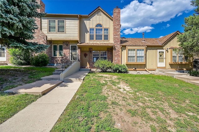 6737 Overland Dr, Colorado Springs, CO 80919 - view of front of house featuring a front lawn, brick siding, a chimney, and board and batten siding
