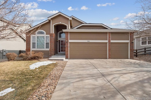 view of front of home with a garage, brick siding, driveway, and fence