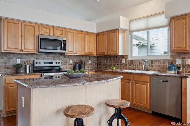 kitchen featuring dark stone counters, a kitchen island, appliances with stainless steel finishes, backsplash, and dark wood-style floors