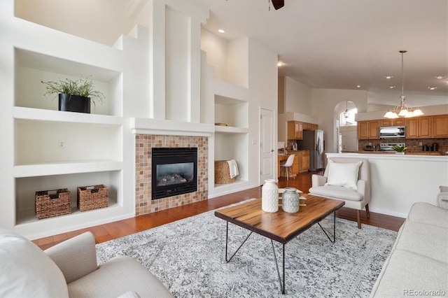 living area with lofted ceiling, built in shelves, a notable chandelier, a fireplace, and light wood finished floors