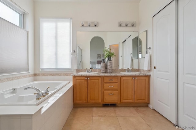 full bathroom with double vanity, a garden tub, tile patterned flooring, and a sink