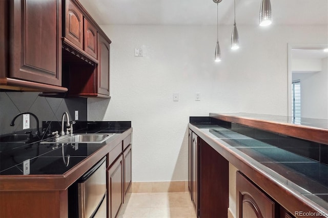 kitchen featuring dishwashing machine, a sink, hanging light fixtures, tasteful backsplash, and dark countertops