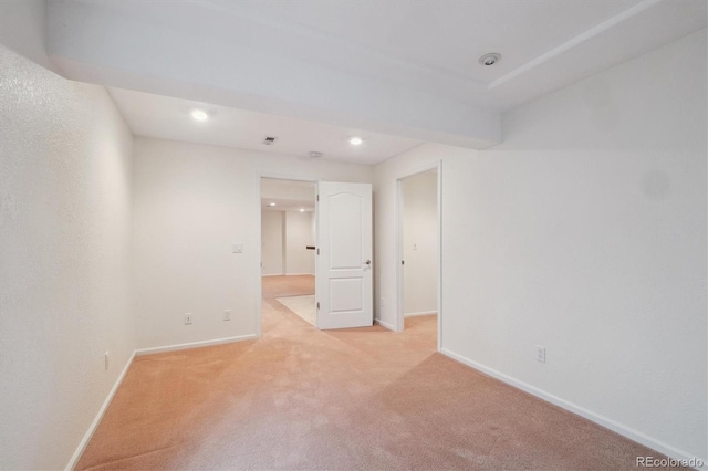 spare room featuring light carpet, visible vents, and baseboards