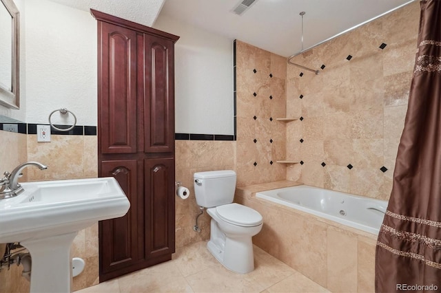 full bathroom with tiled shower / bath, tile walls, visible vents, toilet, and tile patterned floors