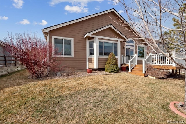 view of front facade featuring a front lawn, fence, and a wooden deck