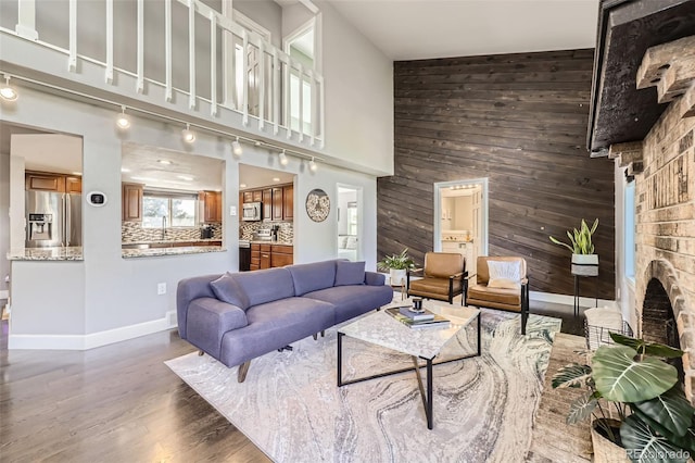 7792 Garrison Ct, Arvada, CO 80005 - living room with wooden walls, wood finished floors, a towering ceiling, baseboards, and a fireplace