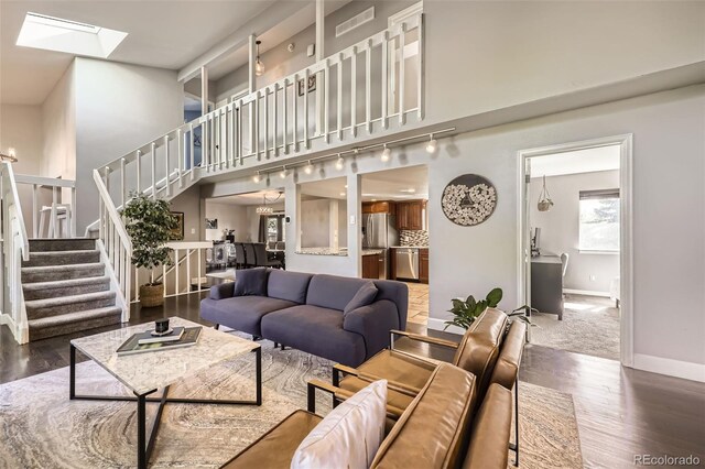 7792 Garrison Ct, Arvada, CO 80005 - living room featuring stairway, a skylight, baseboards, wood finished floors, and rail lighting