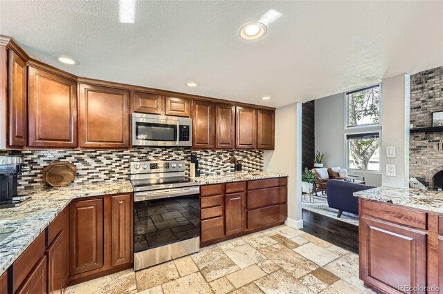 7792 Garrison Ct, Arvada, CO 80005 - kitchen featuring stainless steel appliances, backsplash, recessed lighting, light stone countertops, and a textured ceiling