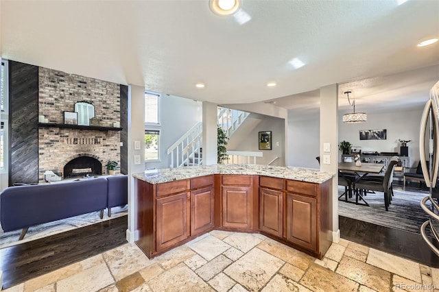 7792 Garrison Ct, Arvada, CO 80005 - kitchen featuring open floor plan, light stone countertops, stone tile floors, a brick fireplace, and hanging light fixtures