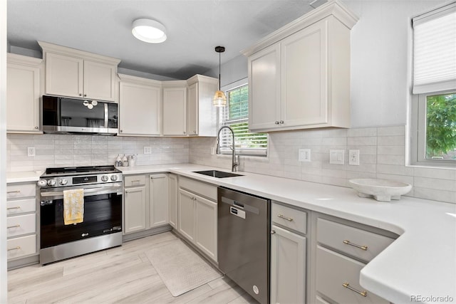 kitchen with appliances with stainless steel finishes, sink, backsplash, and decorative light fixtures