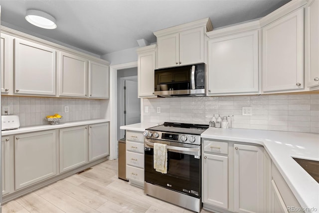 kitchen with tasteful backsplash, white cabinetry, stainless steel appliances, and light hardwood / wood-style floors