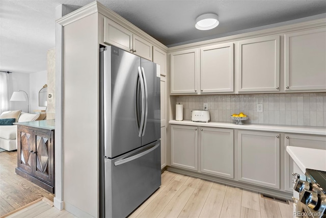 kitchen with tasteful backsplash, appliances with stainless steel finishes, and light hardwood / wood-style floors