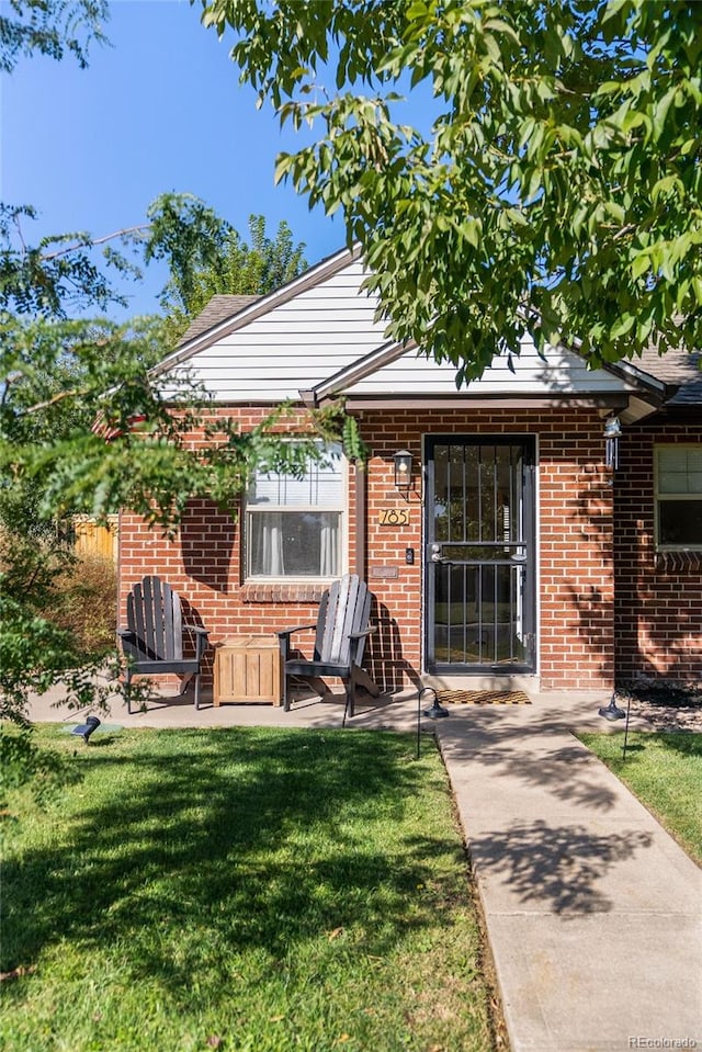 doorway to property featuring a lawn and a patio