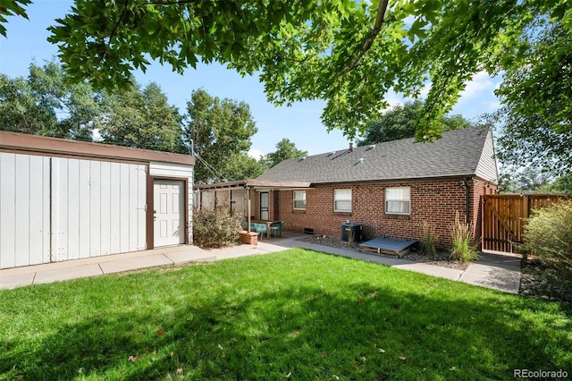 rear view of house with central AC, a yard, and an outbuilding