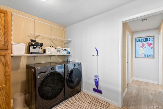 laundry area with light hardwood / wood-style flooring and washing machine and dryer