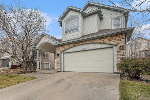 traditional-style home with driveway, stone siding, and an attached garage