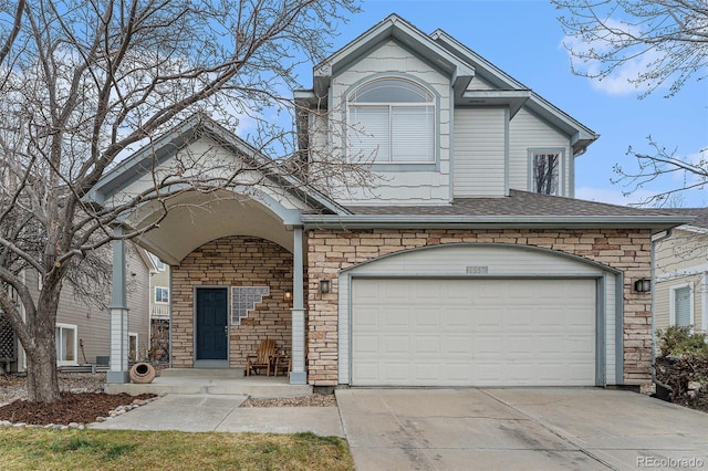 traditional-style house featuring a garage, concrete driveway, a shingled roof, and stone siding