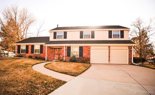 traditional home with brick siding, a front lawn, fence, concrete driveway, and a garage