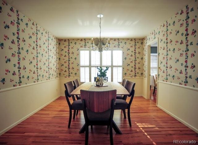 dining space with wallpapered walls, baseboards, wainscoting, light wood-style flooring, and a notable chandelier