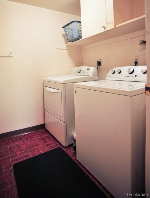 clothes washing area with brick floor, cabinet space, baseboards, and washing machine and clothes dryer