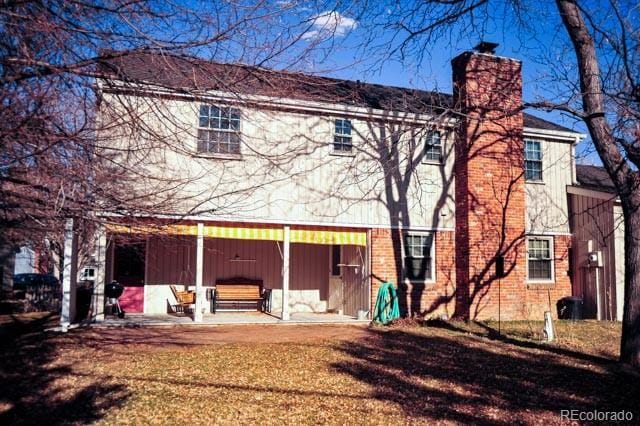 back of house featuring brick siding and a chimney