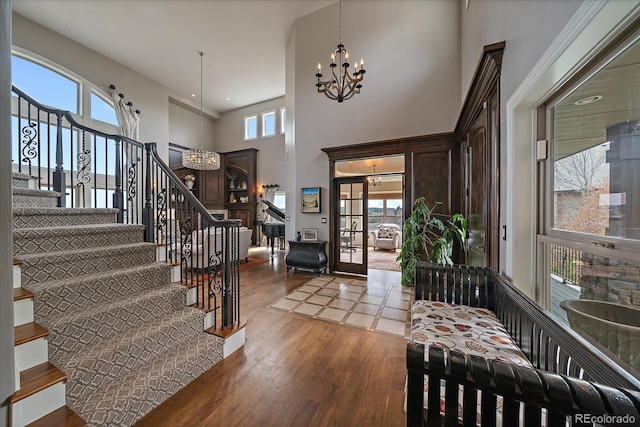 entryway with stairs, an inviting chandelier, a high ceiling, and wood finished floors