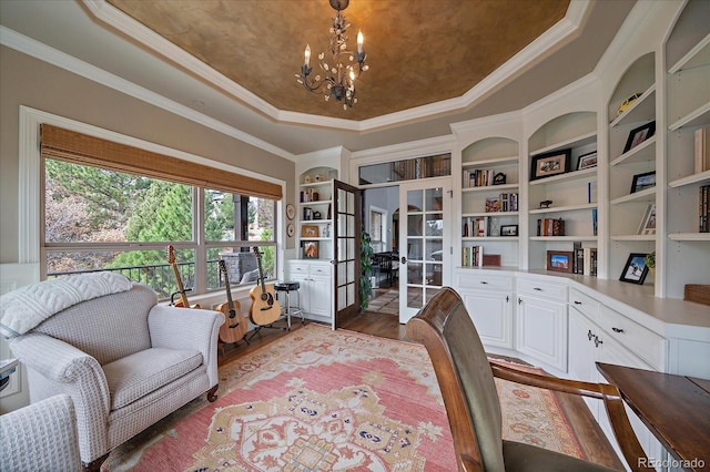 office area with wood finished floors, french doors, a tray ceiling, built in features, and a chandelier