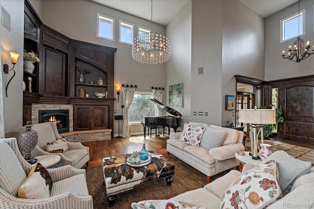 living area with a notable chandelier, a fireplace, a high ceiling, and wood finished floors