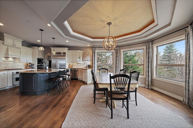 dining room featuring a raised ceiling, an inviting chandelier, recessed lighting, and dark wood-style flooring