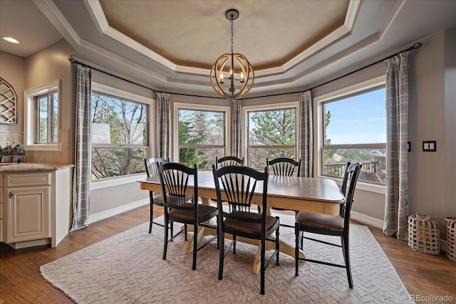 dining room featuring a chandelier, a raised ceiling, dark wood-style flooring, and baseboards