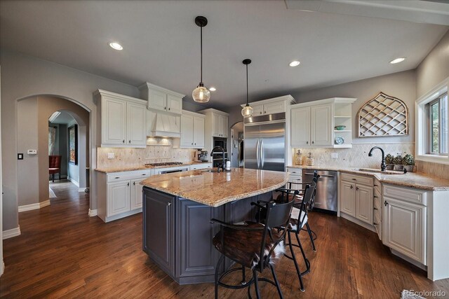kitchen featuring a sink, open shelves, arched walkways, backsplash, and stainless steel appliances