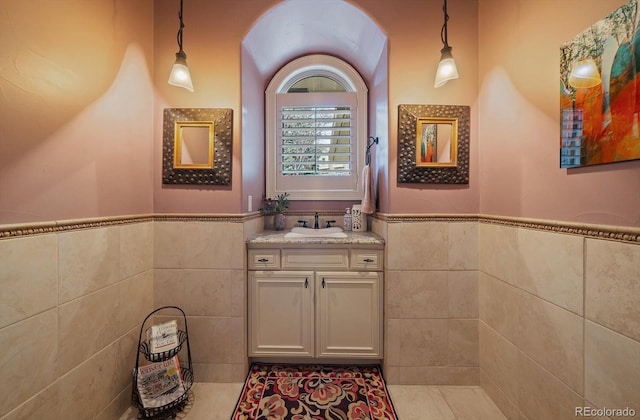 bathroom featuring tile walls, vanity, and a wainscoted wall