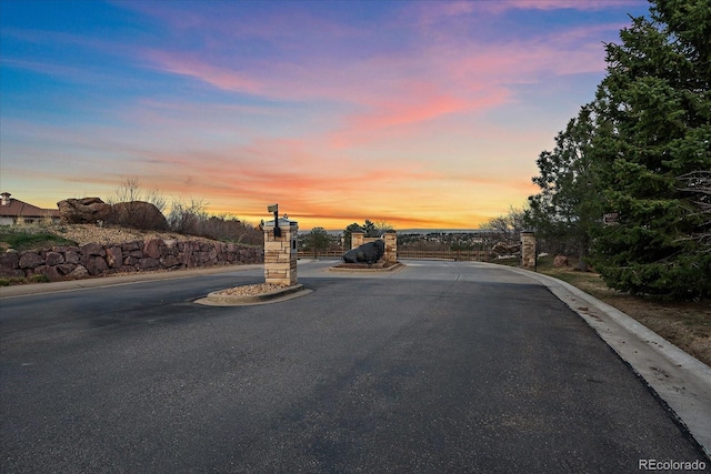 view of street featuring a gated entry and curbs