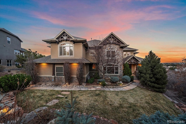 craftsman house with stone siding, stucco siding, and a front yard