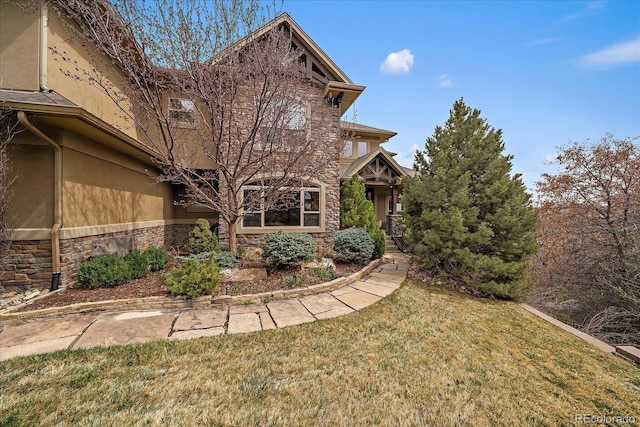 exterior space featuring stucco siding, a front lawn, and stone siding