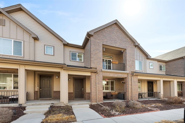 townhome / multi-family property featuring board and batten siding, a porch, brick siding, and central AC