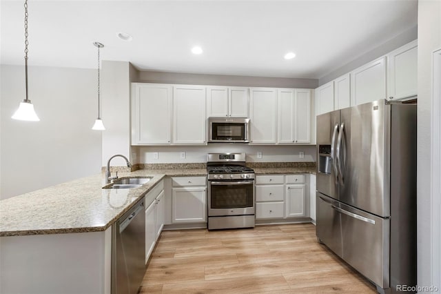 kitchen with light wood-style flooring, a sink, stainless steel appliances, a peninsula, and light stone countertops