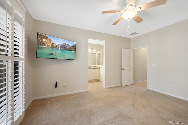 unfurnished bedroom featuring visible vents, baseboards, light colored carpet, and ensuite bathroom