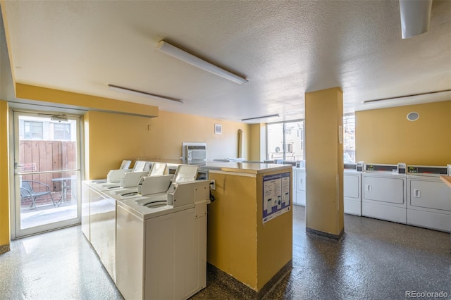 laundry area with a healthy amount of sunlight, washer and dryer, and a textured ceiling