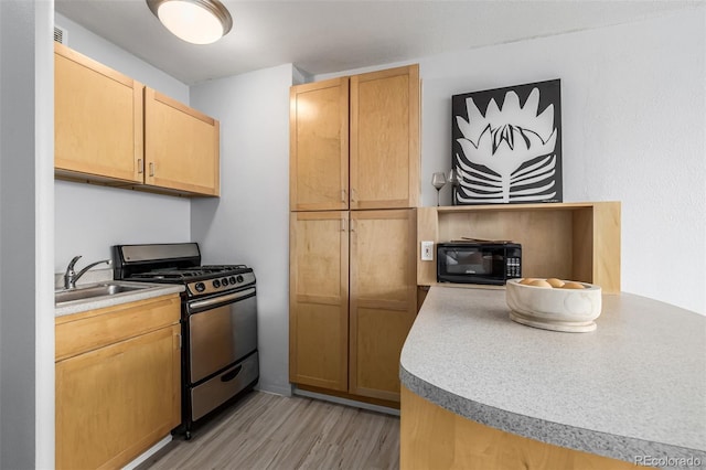 kitchen with sink, gas stove, light brown cabinets, and light wood-type flooring