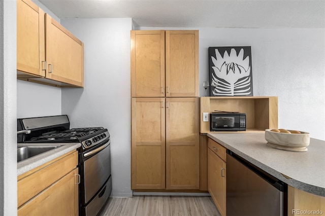 kitchen with gas range, light brown cabinetry, refrigerator, and light wood-type flooring