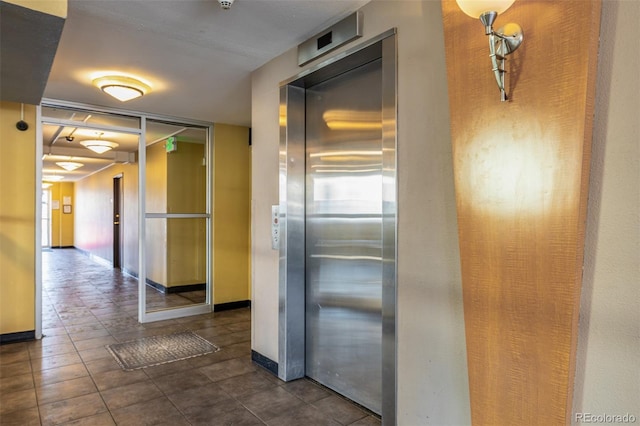 hall featuring elevator and dark tile patterned floors