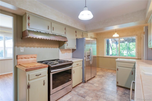 815 Hoyt St, Lakewood, CO 80215 - kitchen featuring stainless steel appliances, healthy amount of natural light, pendant lighting, tile counters, and a wainscoted wall
