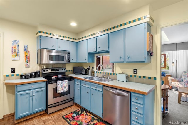 kitchen featuring stainless steel appliances, blue cabinetry, a sink, and recessed lighting