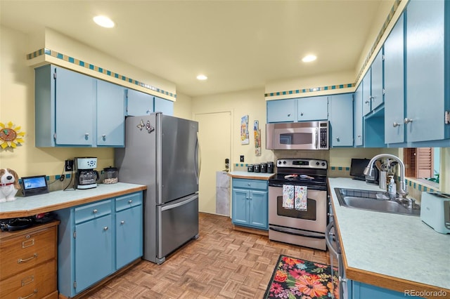 kitchen with appliances with stainless steel finishes, blue cabinets, a sink, light countertops, and recessed lighting