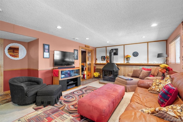 carpeted living area with a textured ceiling, a wood stove, recessed lighting, and wood walls
