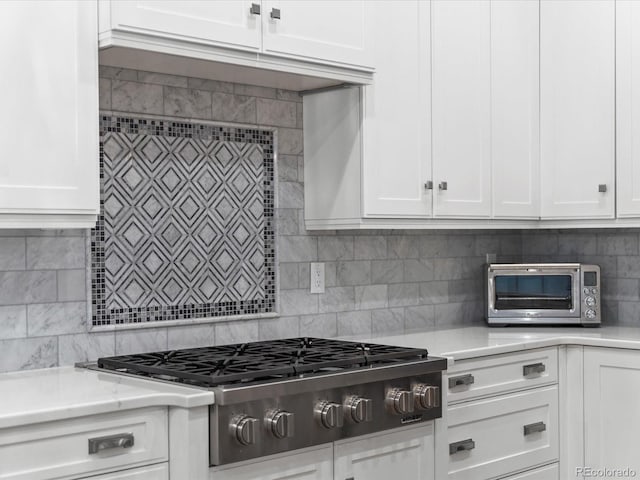 425 Steele St, Denver, CO 80206 - kitchen with stainless steel gas cooktop, white cabinets, tasteful backsplash, and light stone countertops